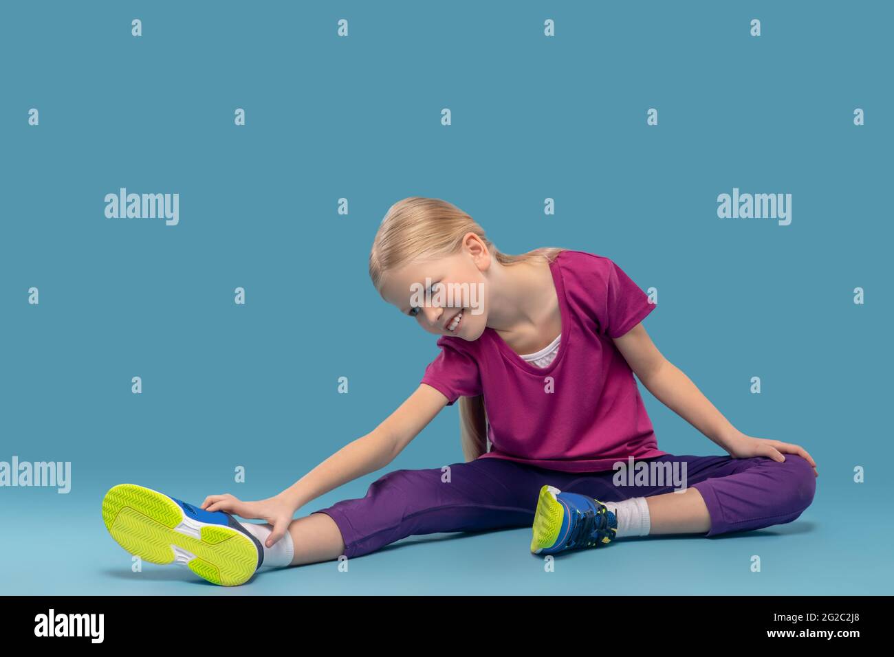 Fille assise sur le sol se pliant à la jambe tendue Banque D'Images
