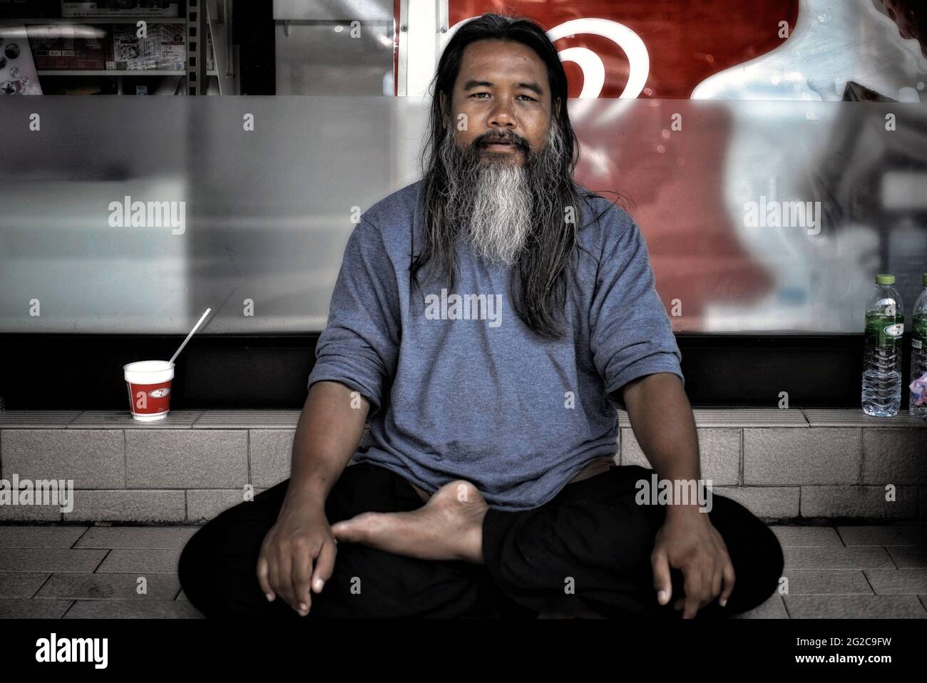 Homme asiatique. Portrait d'un homme thaïlandais barbu assis sur une position de yoga à pattes croisées. Banque D'Images
