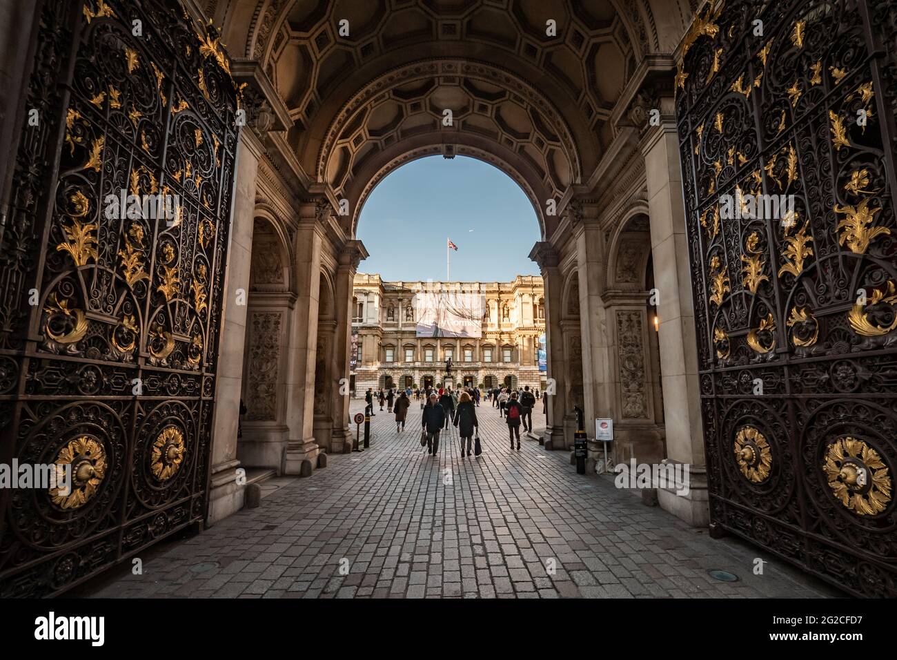 La Royal Academy of Arts, Londres, Angleterre. Une vue large à travers les portes de la RA avec des affiches d'exposition pour Anthony Gormley et Lucien Freud. Banque D'Images