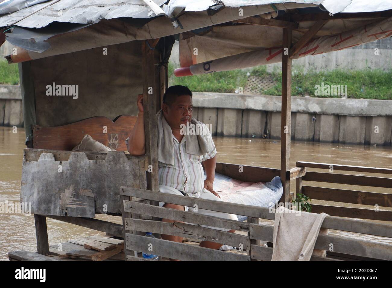Entre Kampung Pulo et Kampung Melayu Kecil, dans la région de Jatinegara, dans l'est de Jakarta, en Indonésie, limitée par la partie du remblai qui retient la normalisation du débit de la rivière Ciliwung, il existe un service de traversée terrestre qui, jusqu'à présent, survit encore dans la capitale. Rohim (42) un homme de stock d'Indramayu, qui est également un chauffeur de Bajaj, prend tour à tour avec son ami Azis (45) qui retourne dans sa ville natale, en courant un service de traversée de bateau traînante pour survivre. (Photo de Kuncoro Widyo Rumpoko/Pacific Press) Banque D'Images