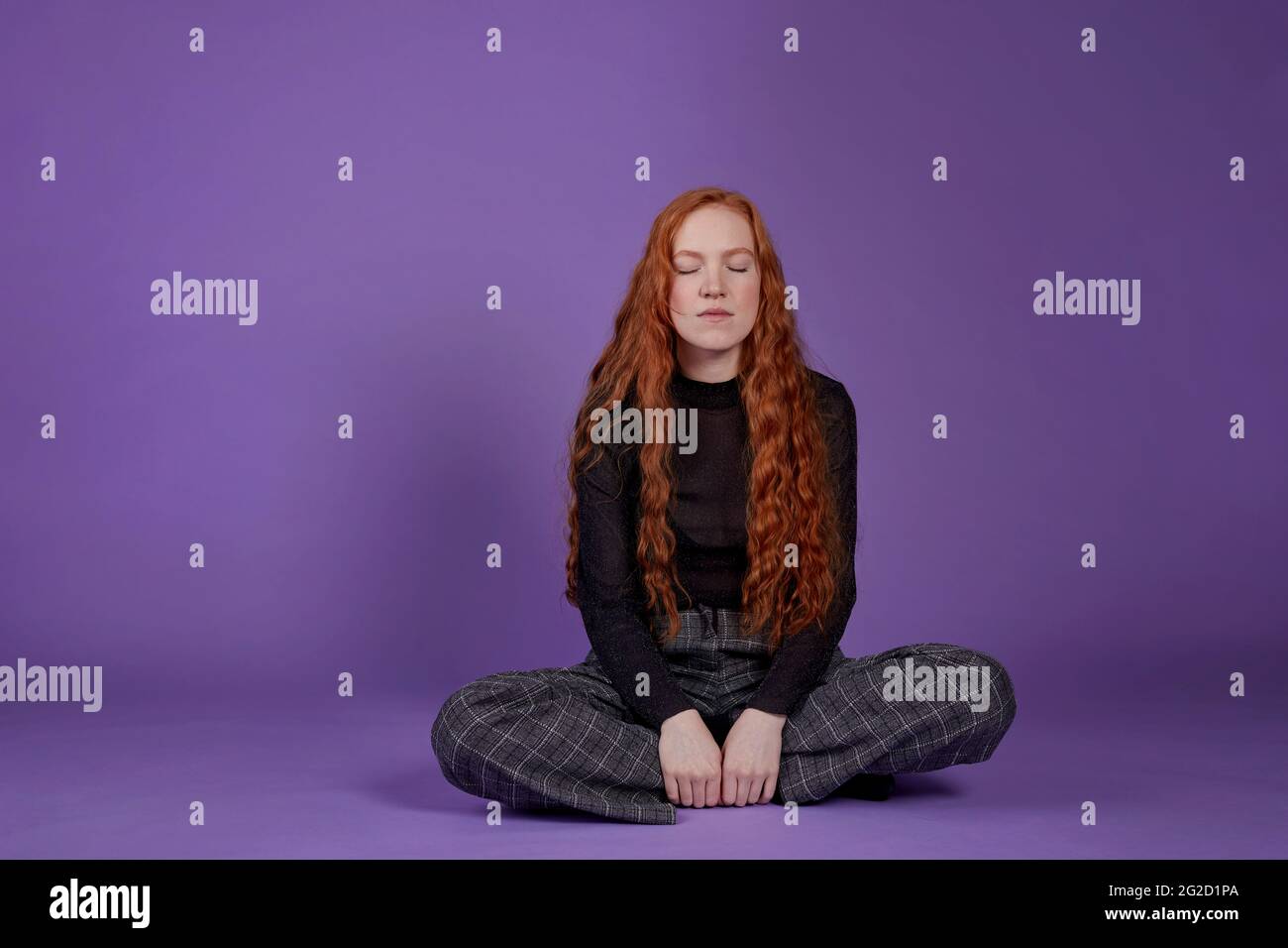 Femme avec les yeux fermés sur fond violet Banque D'Images