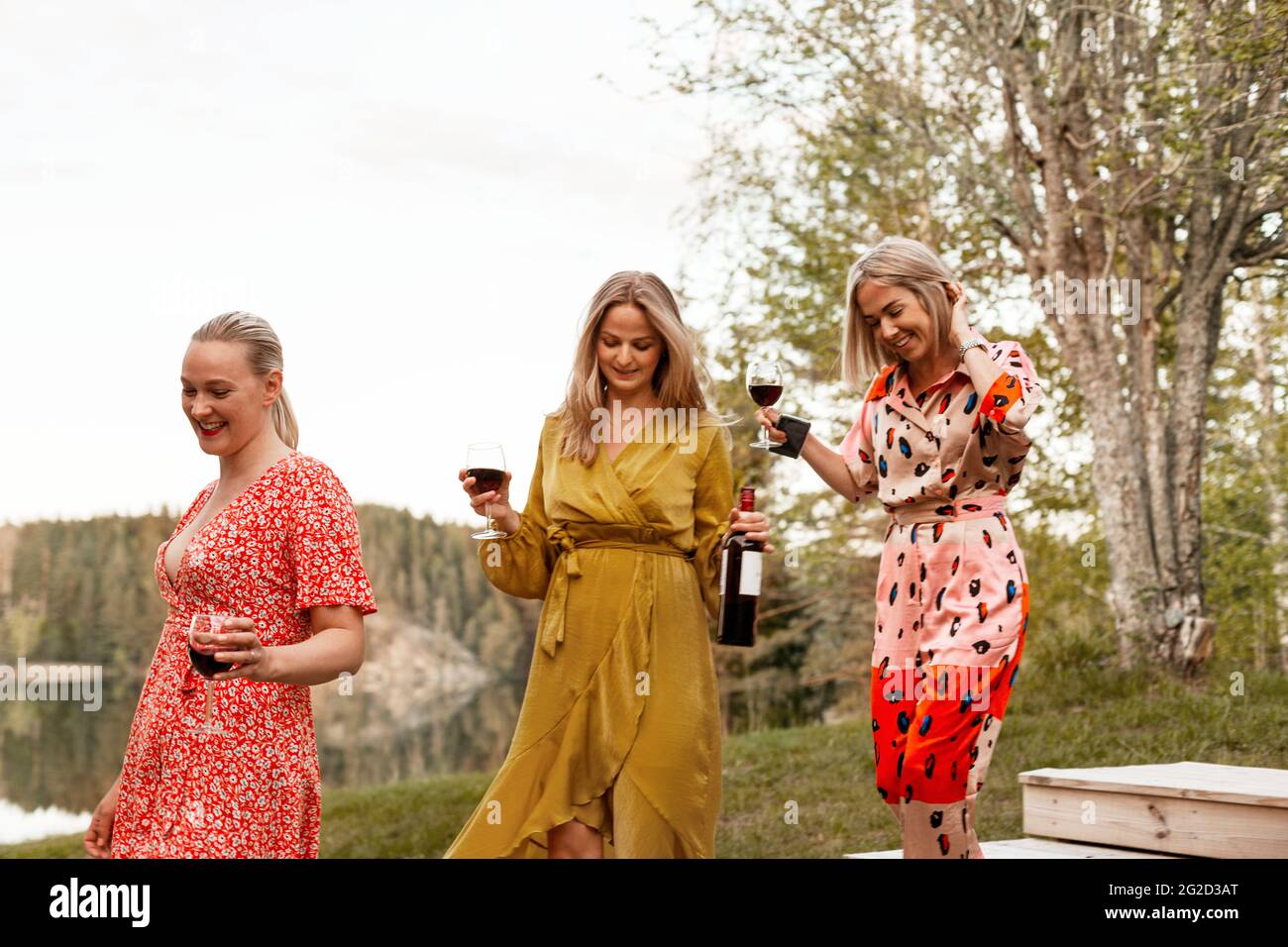 Des amies souriantes tenant des verres à vin dans la cour Banque D'Images