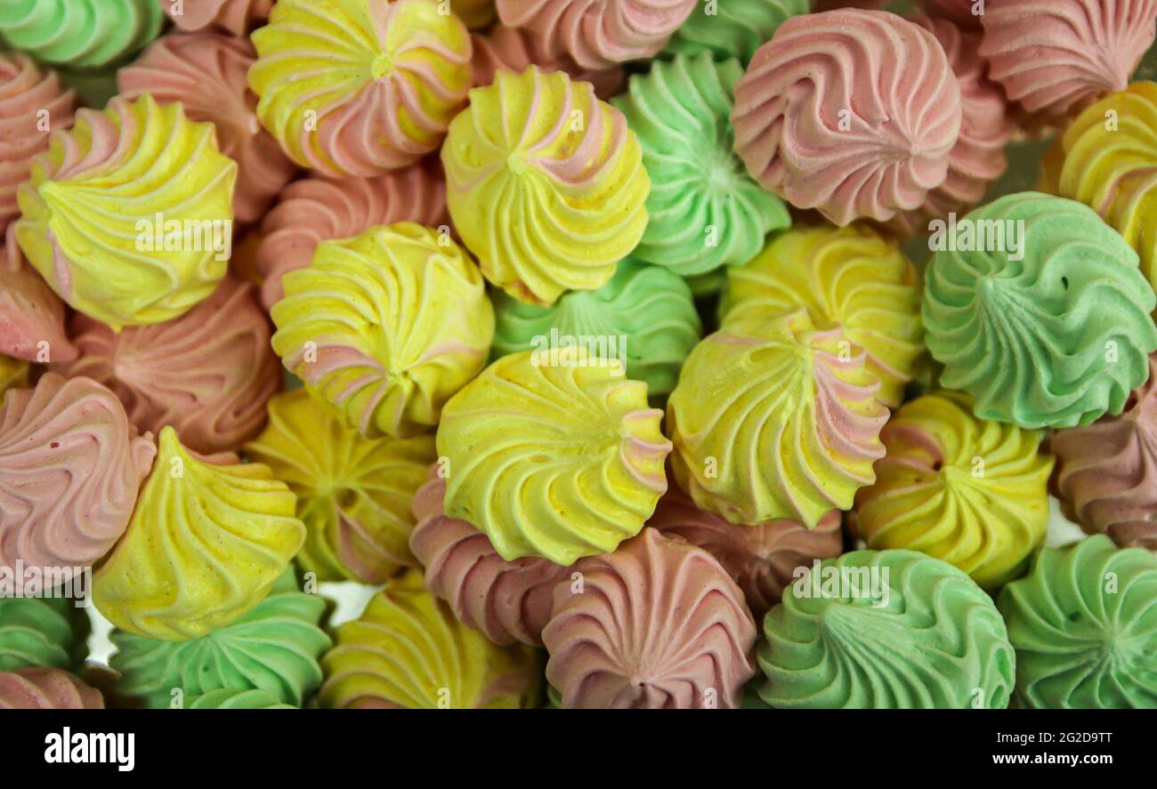 Pâtisseries meringues douces faites maison colorées, desserts jaunes, roses et verts Banque D'Images