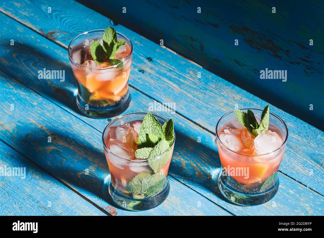 Boissons au jus de citron maison avec glace, fraises fraîches et menthe, limonade en verre sur table rustique en bois bleu Banque D'Images
