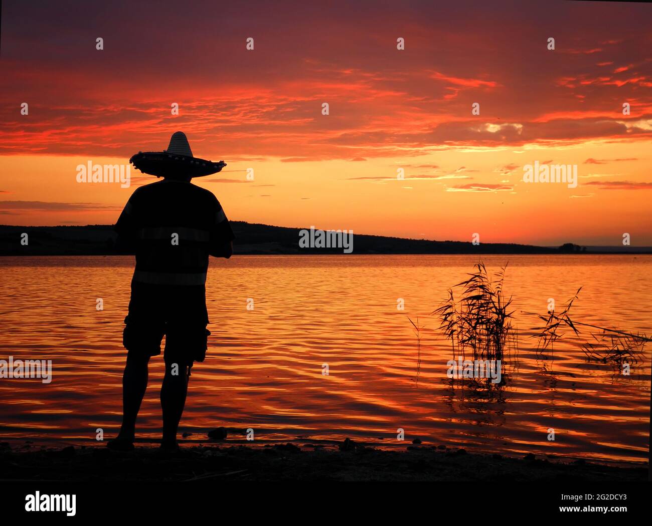 Un pêcheur pêche silhouette au coucher du soleil. La pêche en eau douce, les captures de poisson Banque D'Images