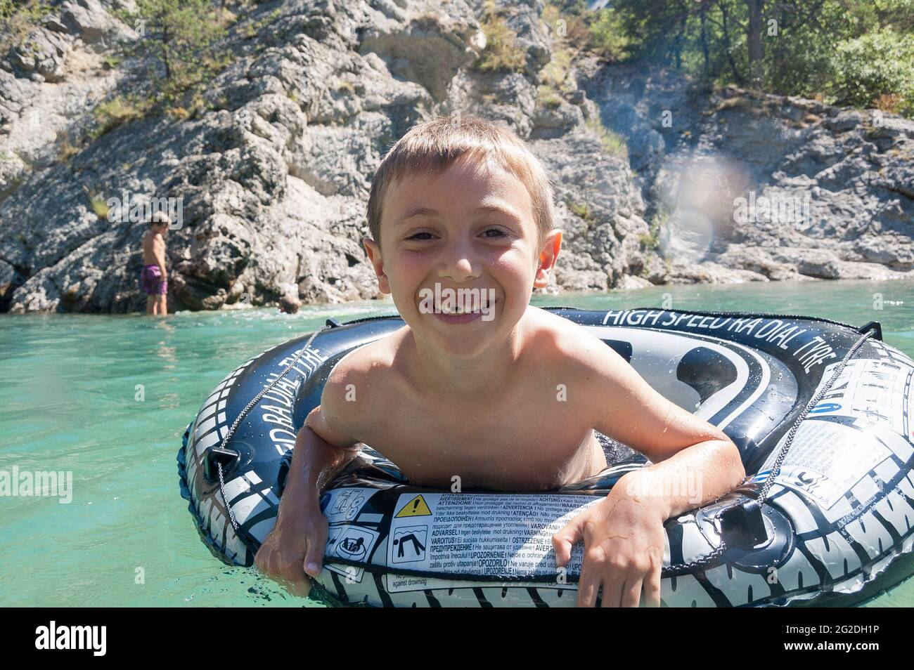 Un enfant flotte sur les rapides d'une rivière en France sur un anneau en caoutchouc. Banque D'Images