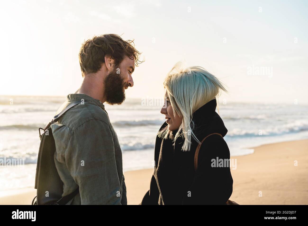 Couple heureux romantique en amour debout sur le rivage à la plage sauvage - Boyfriend et petite amie portant des vêtements frais et sac à dos vintage debout moi Banque D'Images