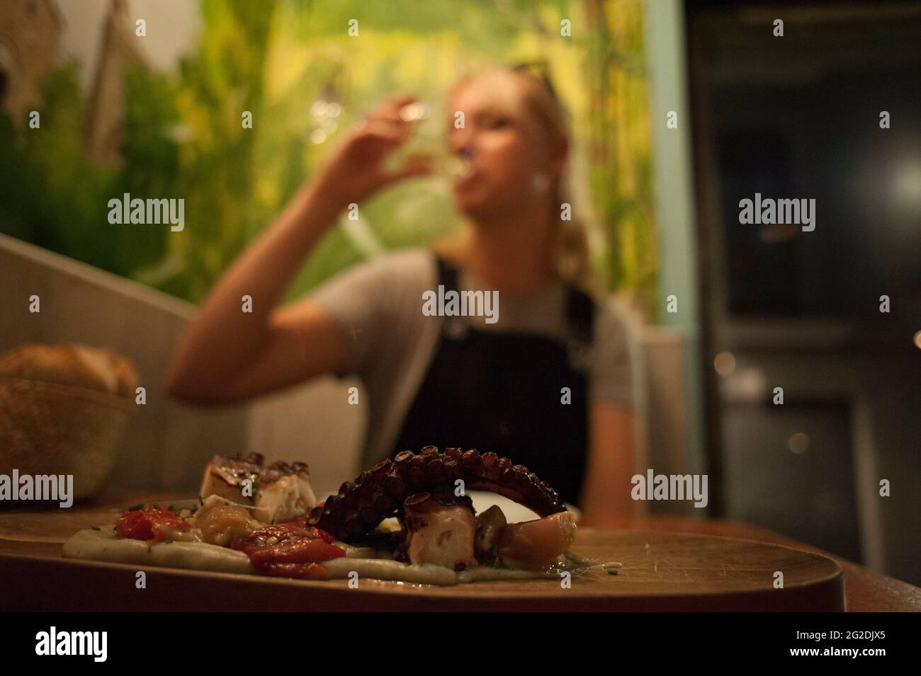 Une femme boit un verre de vin en arrière-plan d'une assiette de délicieux fruits de mer dans un restaurant de Barcelone Banque D'Images