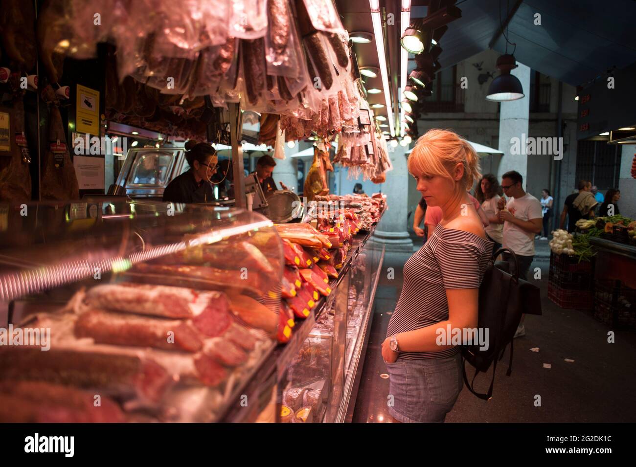 Une femme dans un marché alimentaire dans la ville espagnole de Bareclona regardant des stands de nourriture et des produits. Banque D'Images