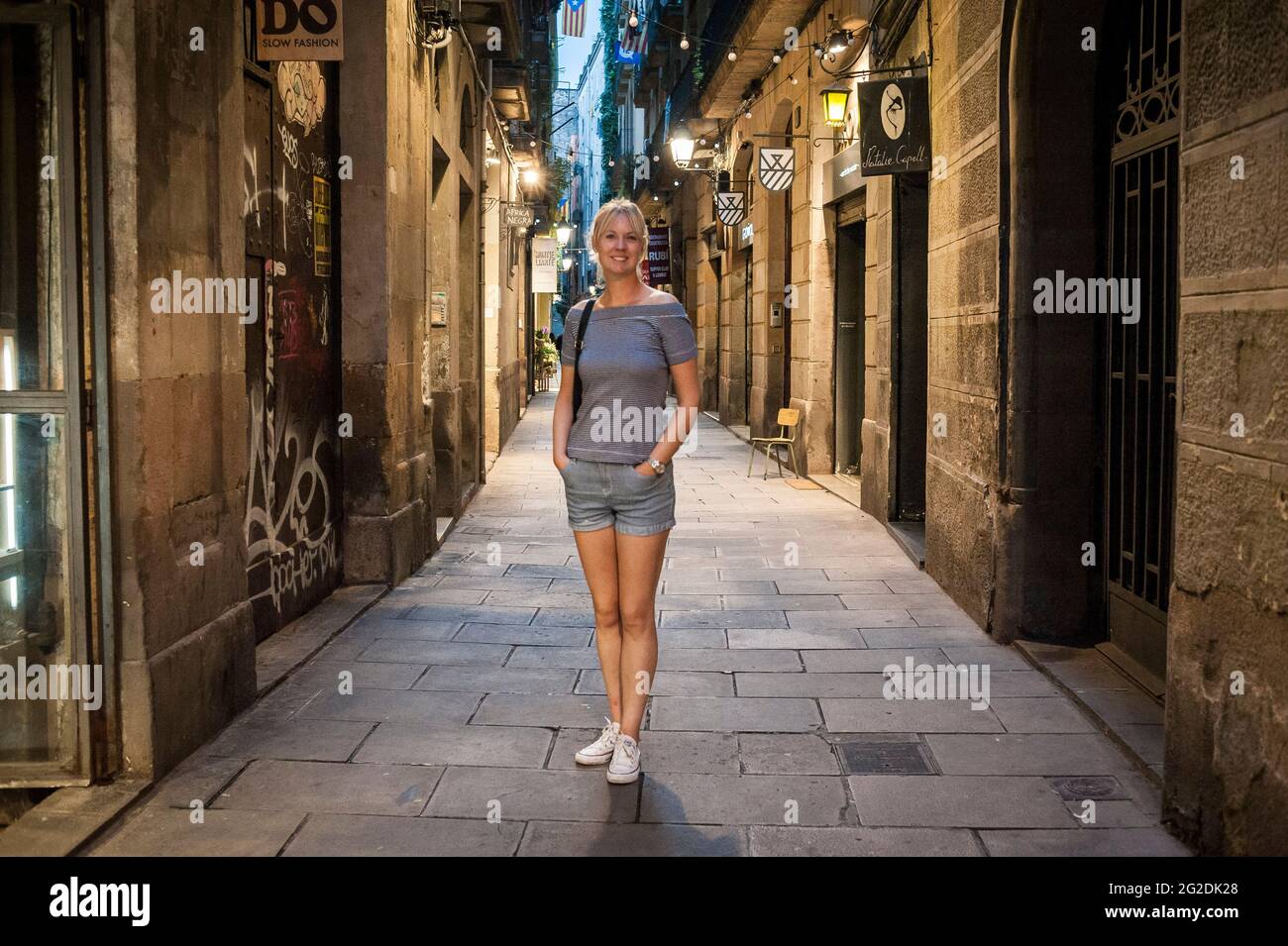 Une femme se tient dans une rue étroite de Barcelone le soir. Banque D'Images