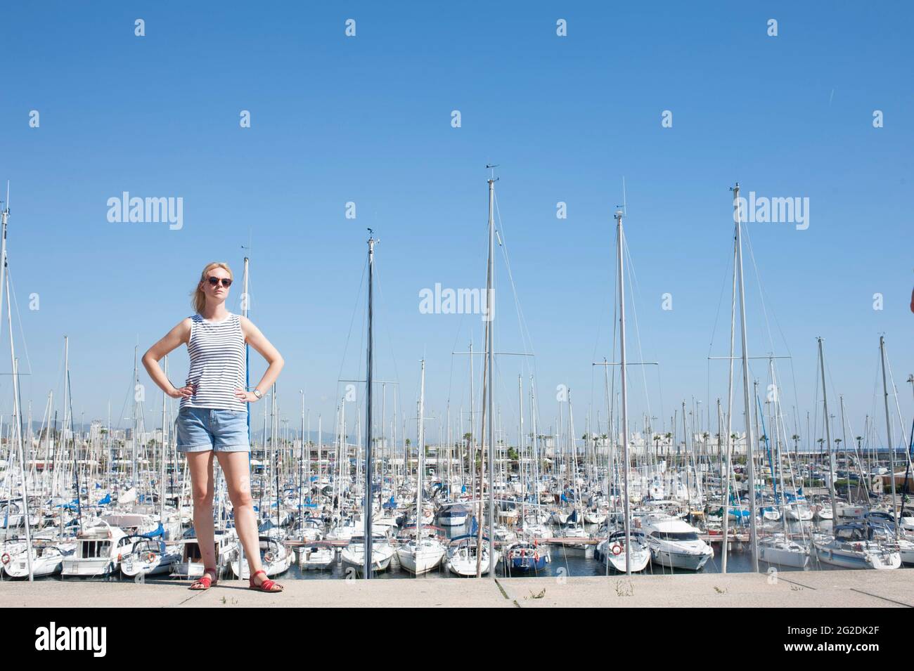 Une personne debout devant de nombreux mâts de nombreux yachts à voile dans une marina de Barcelone, Espagne Banque D'Images
