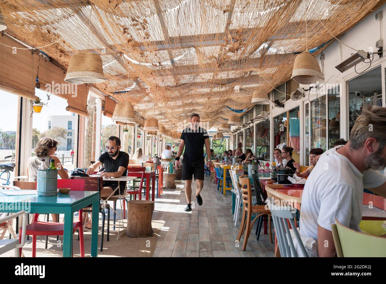 Un homme revient à sa table dans un restaurant espagnol lumineux et ensoleillé sur la plage de Barcelone, au bord de la mer Banque D'Images