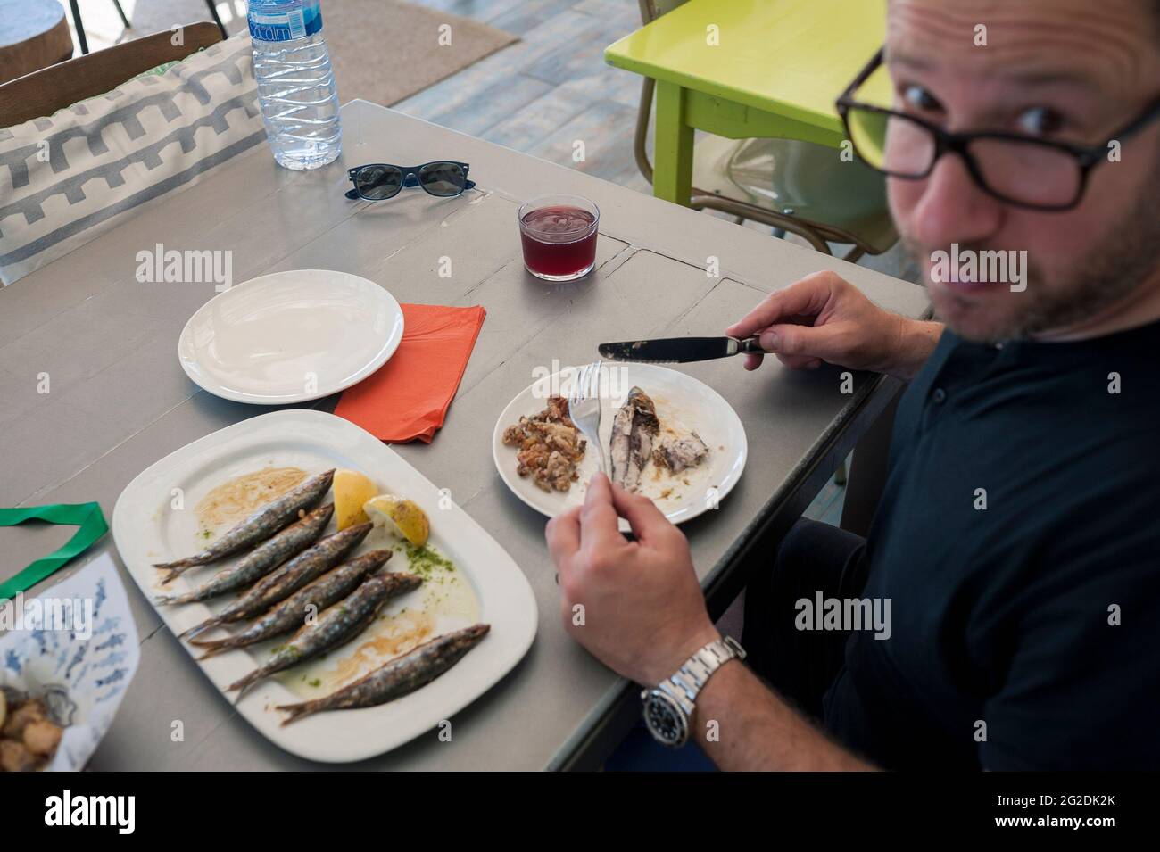 Un homme s'assoit à une table dans un restaurant de Barcelone en mangeant une assiette de sardines fraîches. Banque D'Images