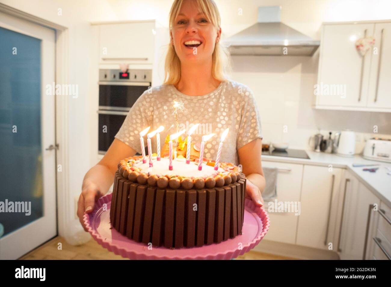 Une mère tient un gâteau d'anniversaire pour une petite fille à son 7e anniversaire Banque D'Images