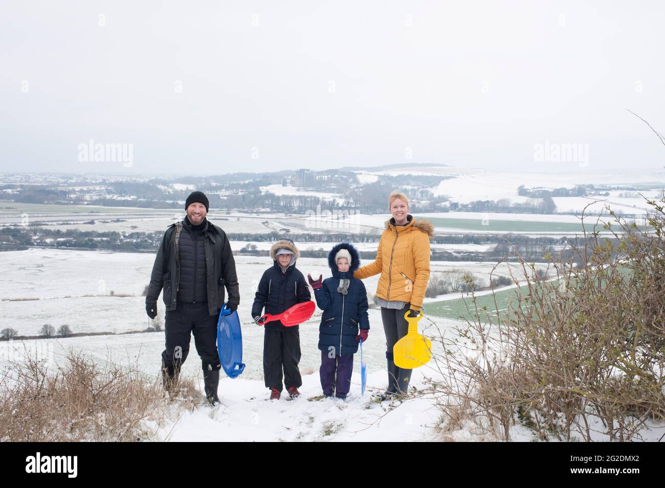 Une famille s'amuse à traîneaux sur Mill Hill à Shoreham-by-Sea, West Sussex après une légère couverture de neige au sol. Banque D'Images