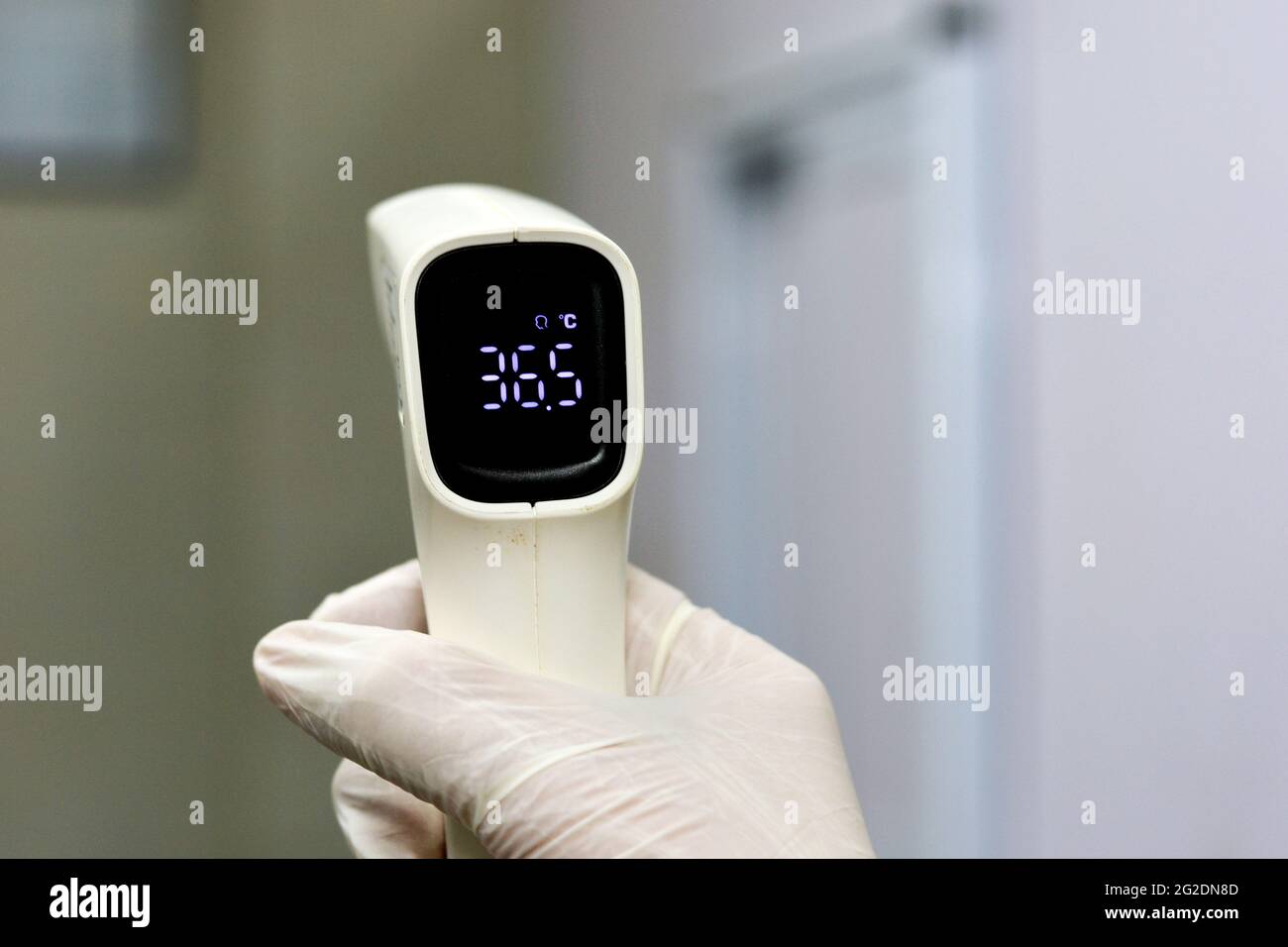 Thermomètre numérique frontal infrarouge sans contact tenu par un personnel médical qui vérifie la température du corps à la recherche de symptômes de virus Banque D'Images