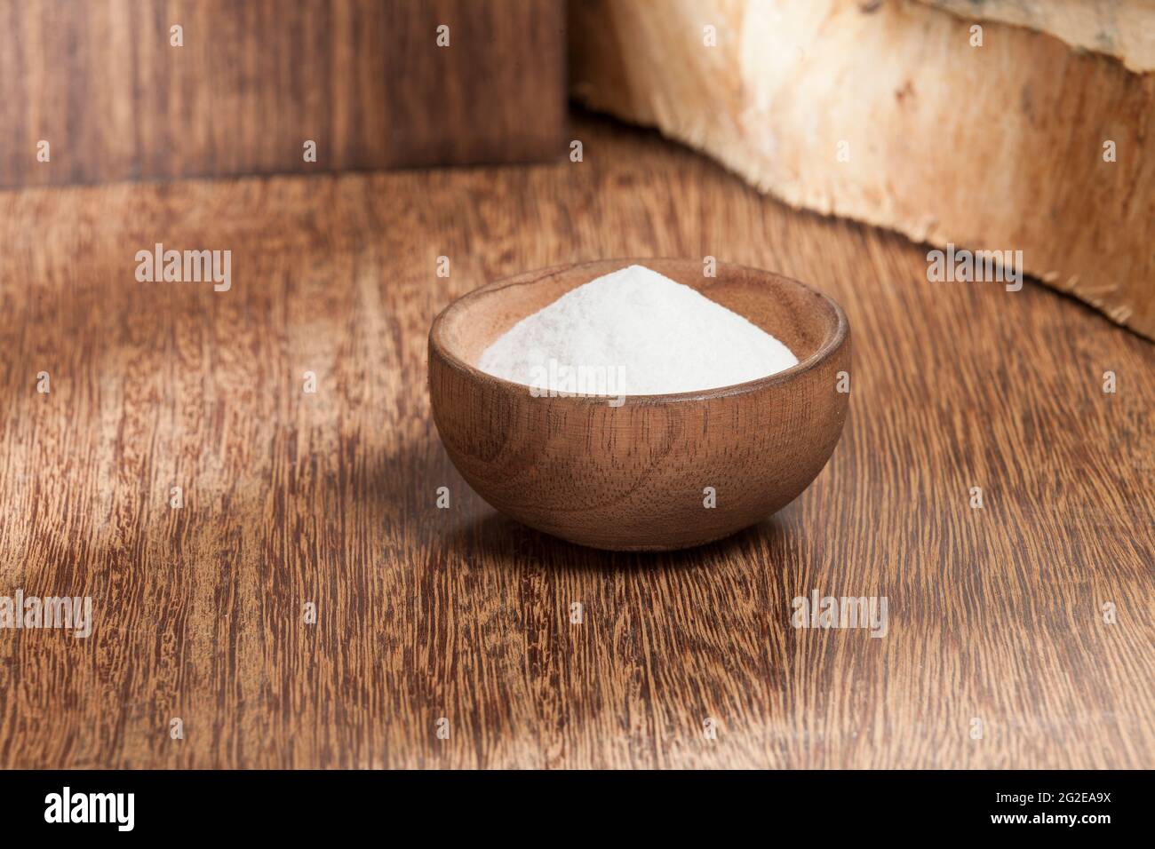 Bicarbonate de soude dans un bol en bois; photo sur fond en bois. Banque D'Images