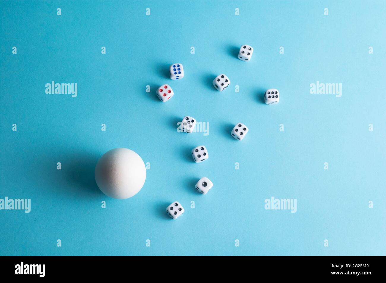 Mise en page minimale avec un œuf blanc et des dés sur fond bleu Banque D'Images
