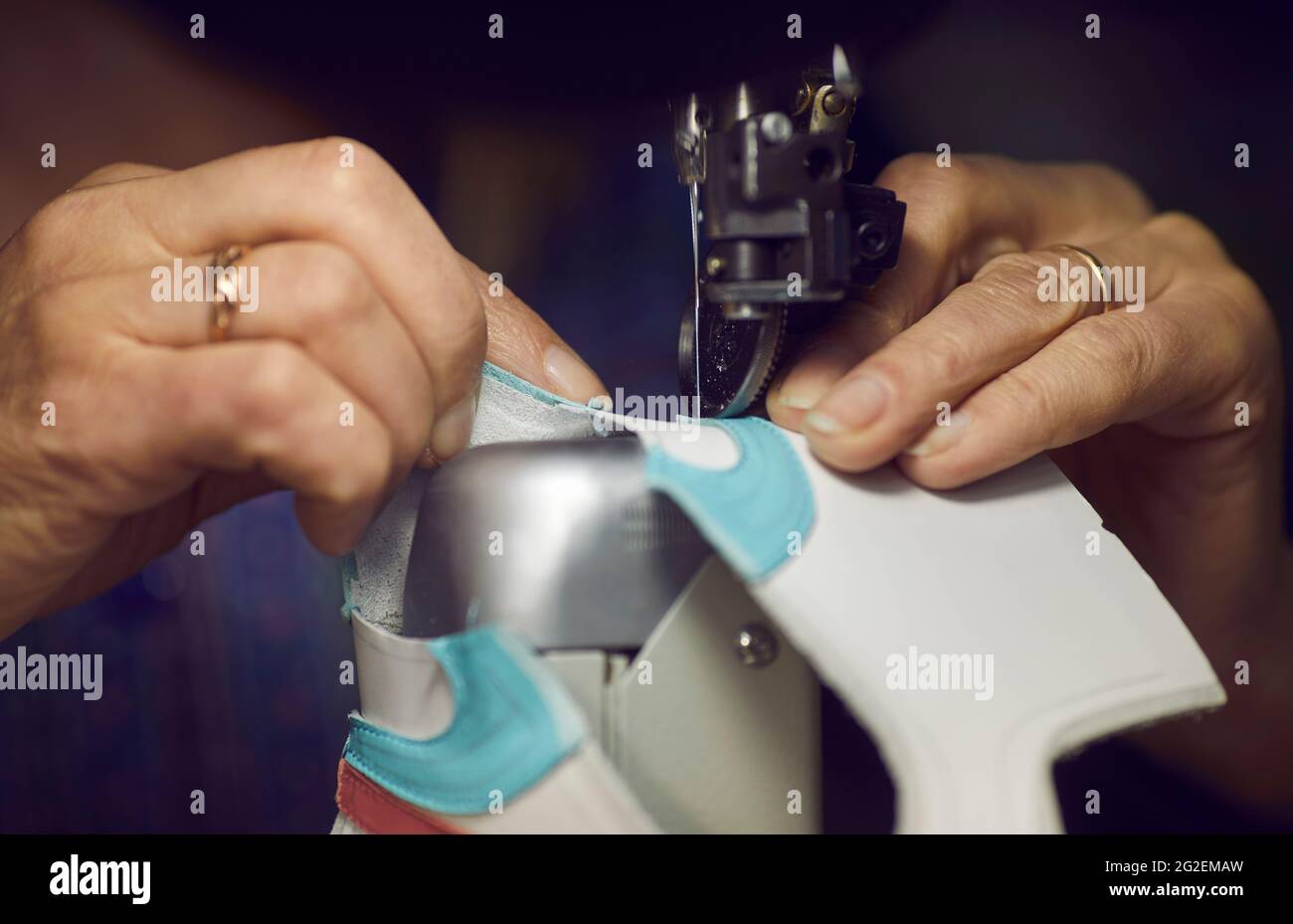 Un travailleur de l'usine de chaussures utilisant une machine à coudre pour faire des détails pour les nouvelles baskets en cuir Banque D'Images