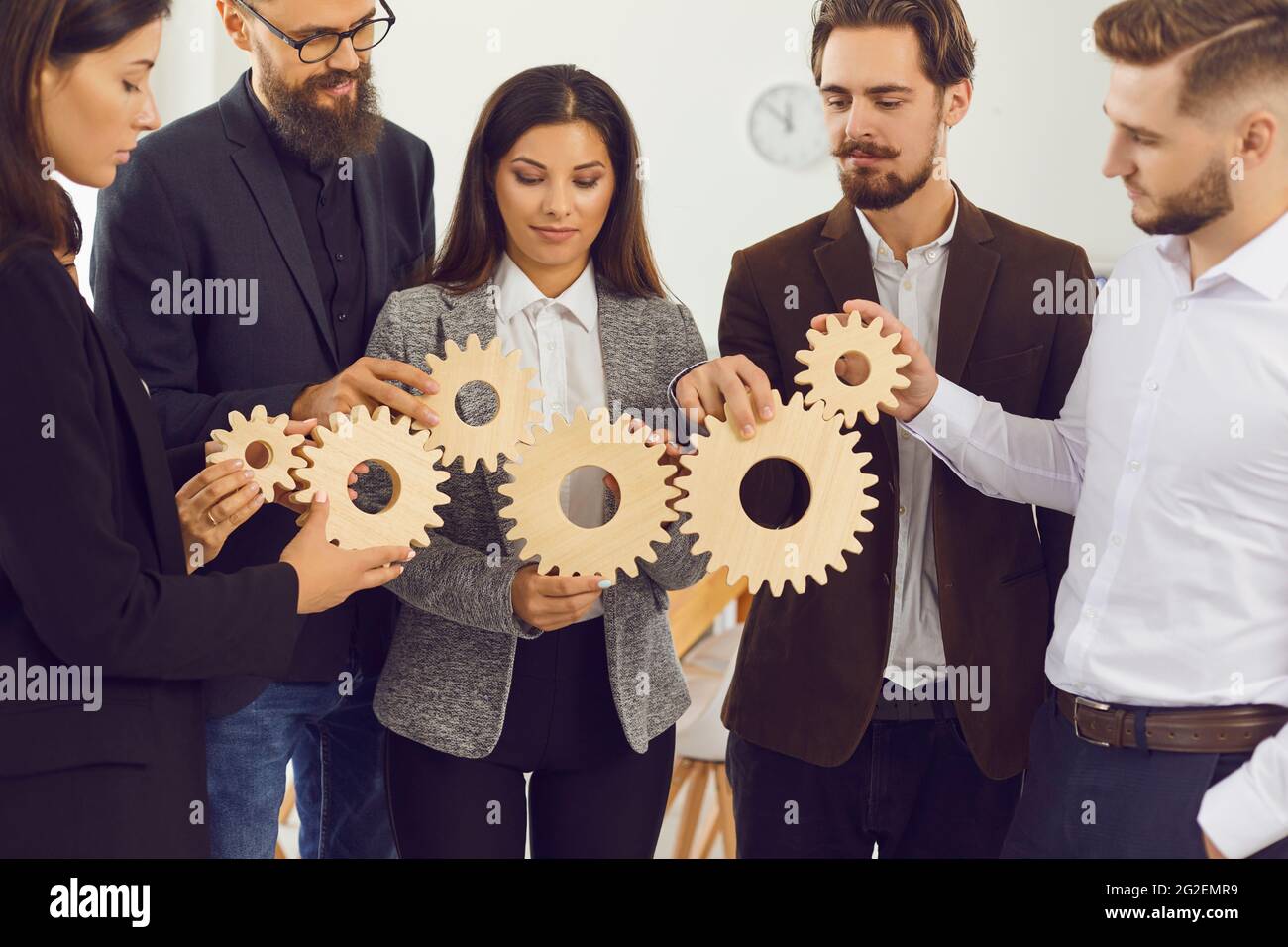 De jeunes dirigeants d'entreprise se joignent aux engrenages pour faire la métaphore d'une gestion et d'une collaboration efficaces Banque D'Images