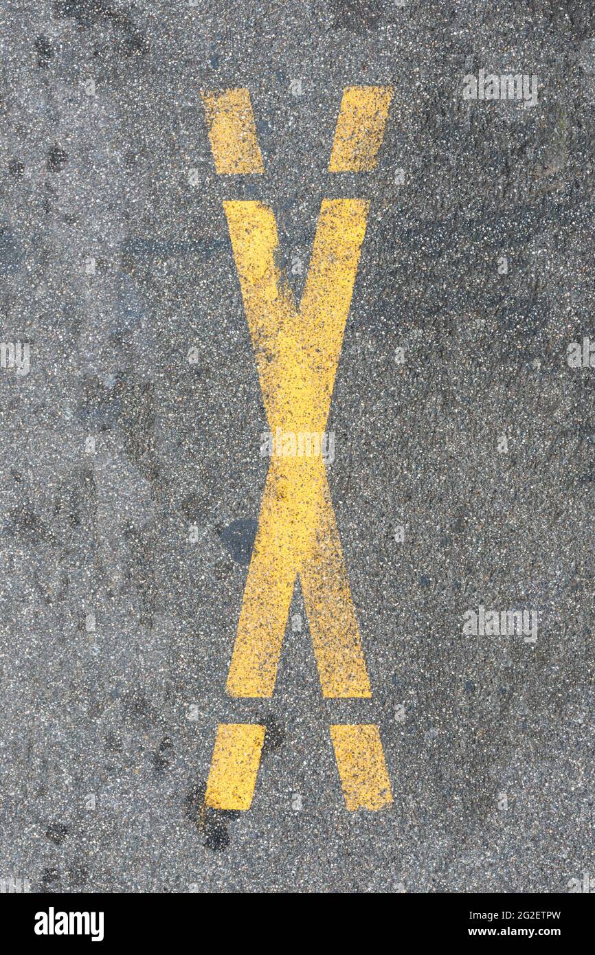 La lettre X est pulvérisée de peinture jaune sur la rue Banque D'Images
