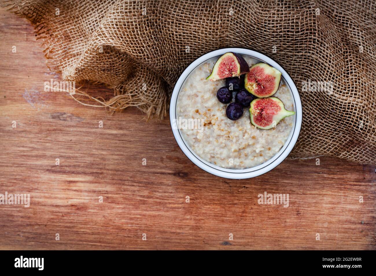 vue de dessus d'un bol d'avoine en acier surmontée de figues et de bleuets sur une surface rustique Banque D'Images