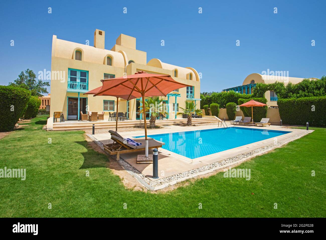 Villa de luxe show home dans un complexe tropical de vacances d'été avec piscine et chaises longues dans le jardin Banque D'Images