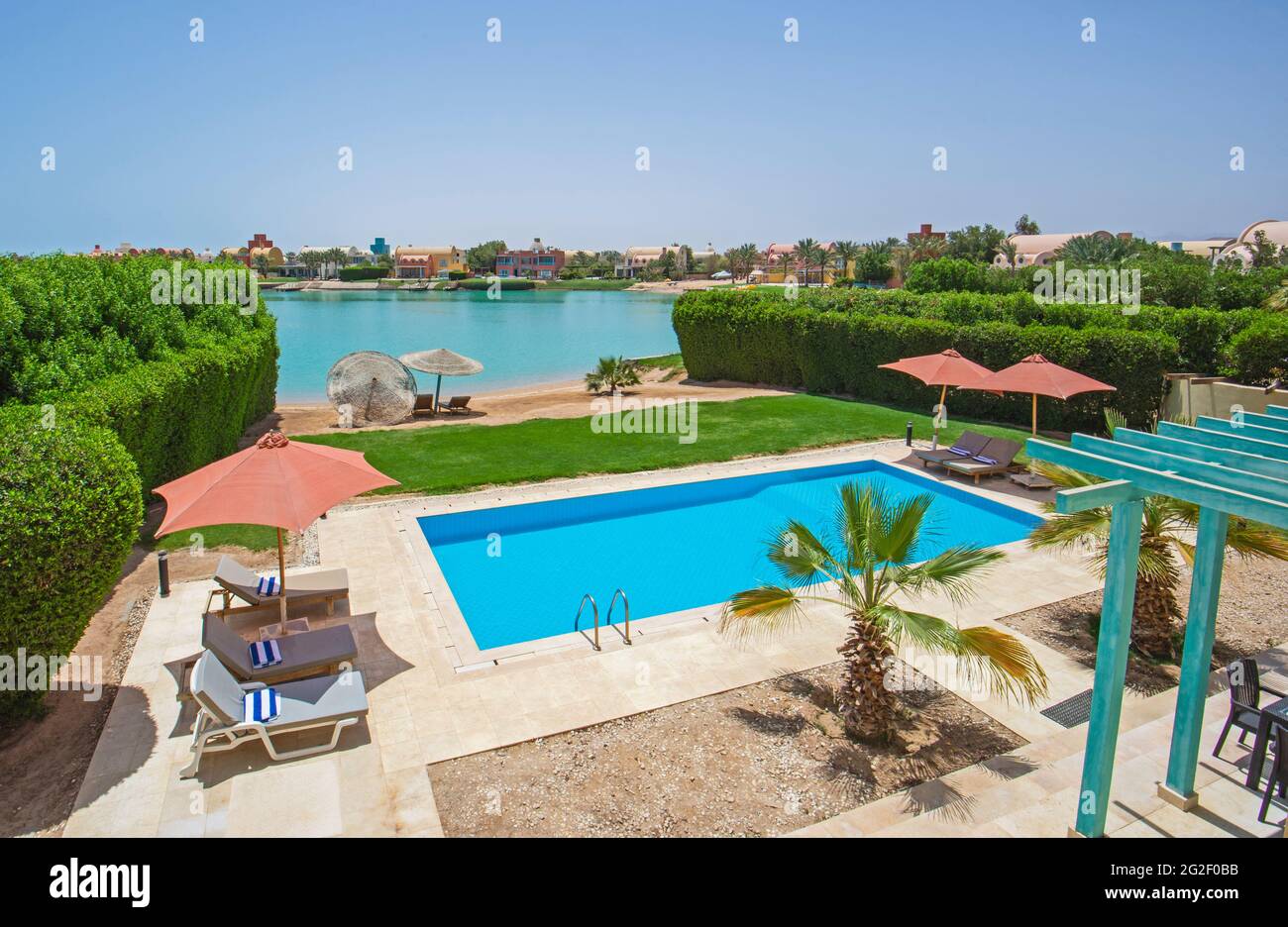 Jardin de villa de luxe show home dans un complexe tropical de vacances d'été avec piscine et chaises longues Banque D'Images