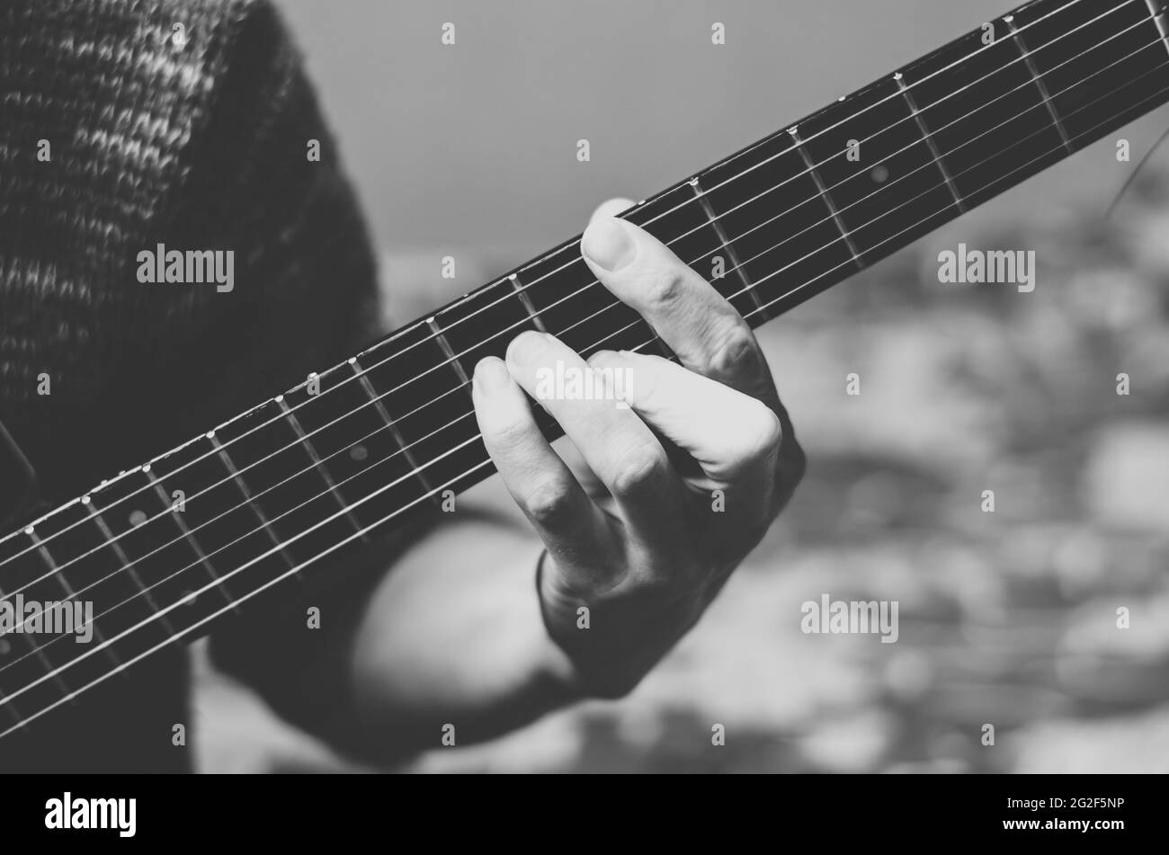 Photo en noir et blanc d'un musicien jouant de la guitare. Doigts sur un fretboard de guitare gros plan Banque D'Images