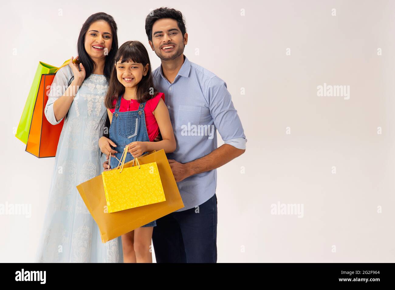 PORTRAIT D'UNE FAMILLE HEUREUSE POSANT AVEC DES SACS À PROVISIONS À LA MAIN Banque D'Images