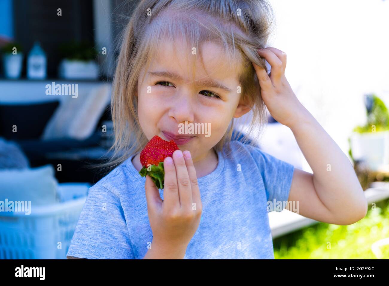 petite fille blonde mangeant des fraises fraîches Banque D'Images