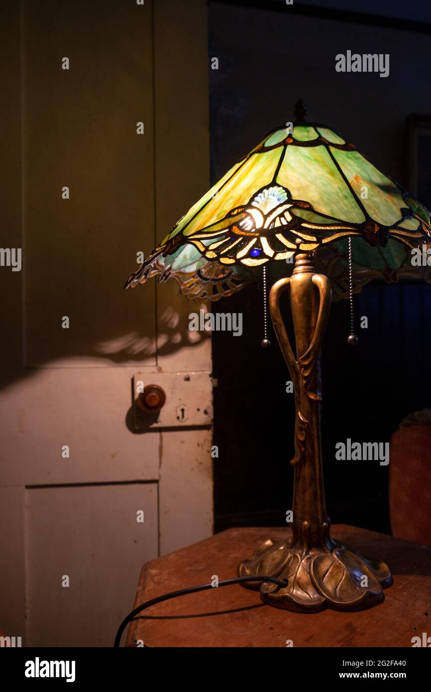 Une lampe Art nouveau avec abat-jour en verre teinté de style Tiffany créant de belles ombres. --- UN week-end à Brooklyn House, Martham Banque D'Images