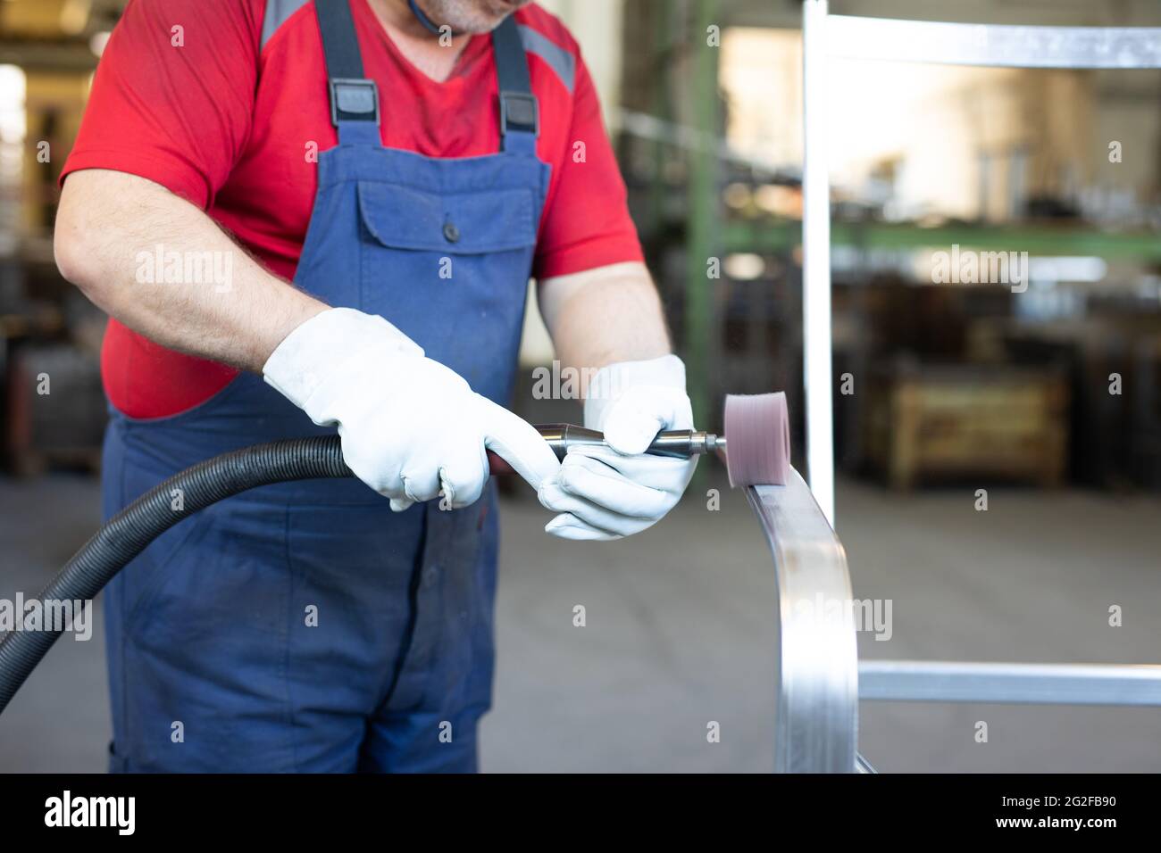 Employé de collier bleu pour polir un morceau de métal dans une usine de fabrication. Polisseuse travaillant en usine. Banque D'Images