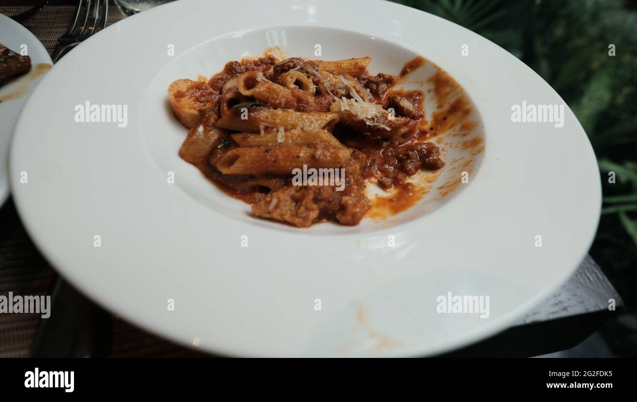 Pâtes italiennes à moitié mangées avec sauce tomate et parmesan sur une assiette blanche Eating out asseyez-vous assis autour d'un repas décontracté sans en-cas Banque D'Images