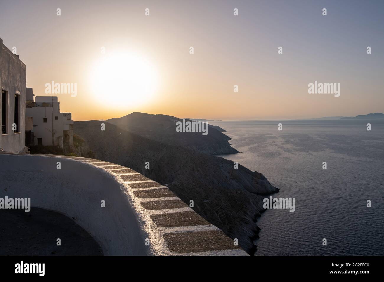 L'île de Folegandros au coucher du soleil. Cyclades, Grèce. Vue à couper le souffle sur la mer Égée depuis les hautes falaises du village de chora, le soleil brille sur un ciel de couleur orange Banque D'Images