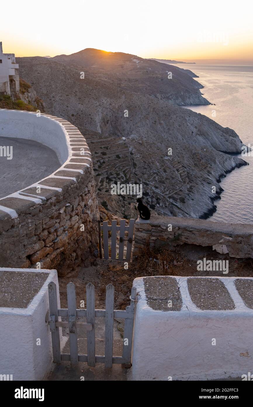 L'île de Folegandros au coucher du soleil. Cyclades, Grèce. Petite porte et mur blanchi à la chaux, vue sur la mer Égée depuis les hautes falaises du village de chora, Banque D'Images