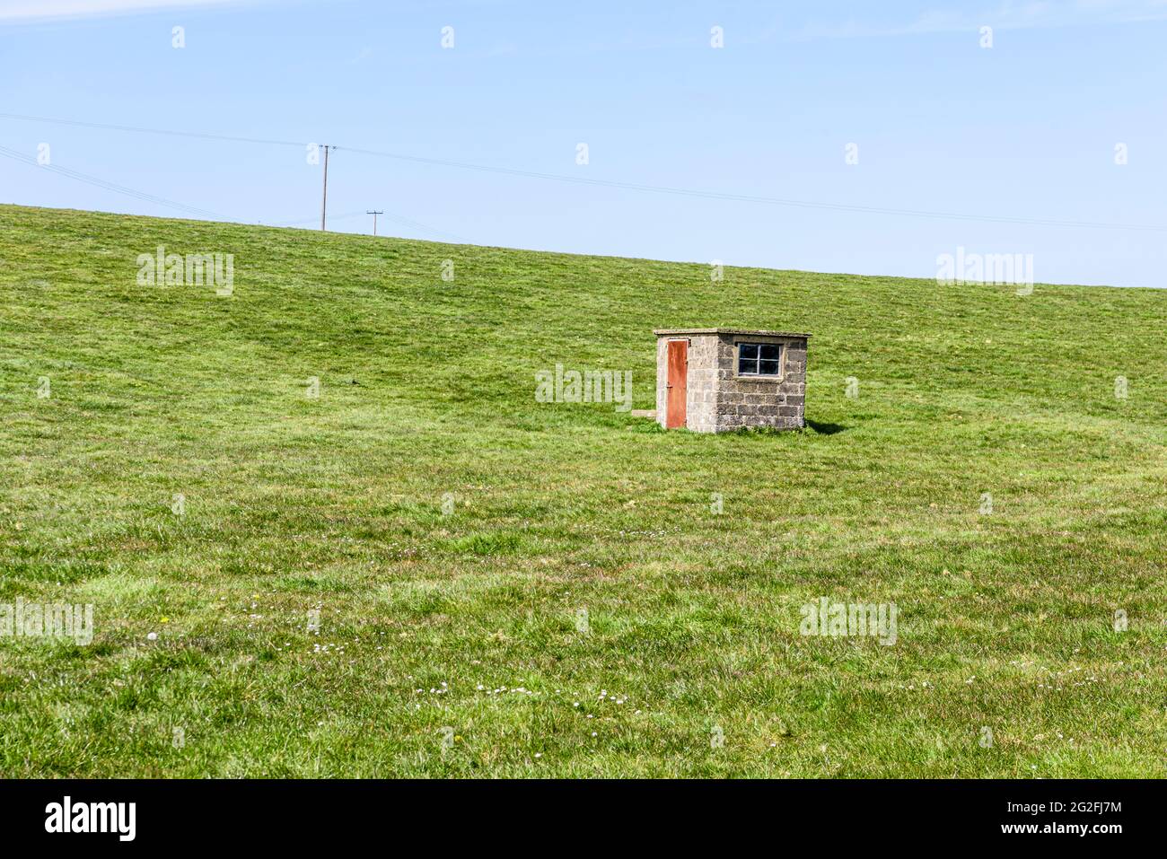 Station de pompage de briques à côté d'un puits dans un creux au milieu d'un champ. Banque D'Images
