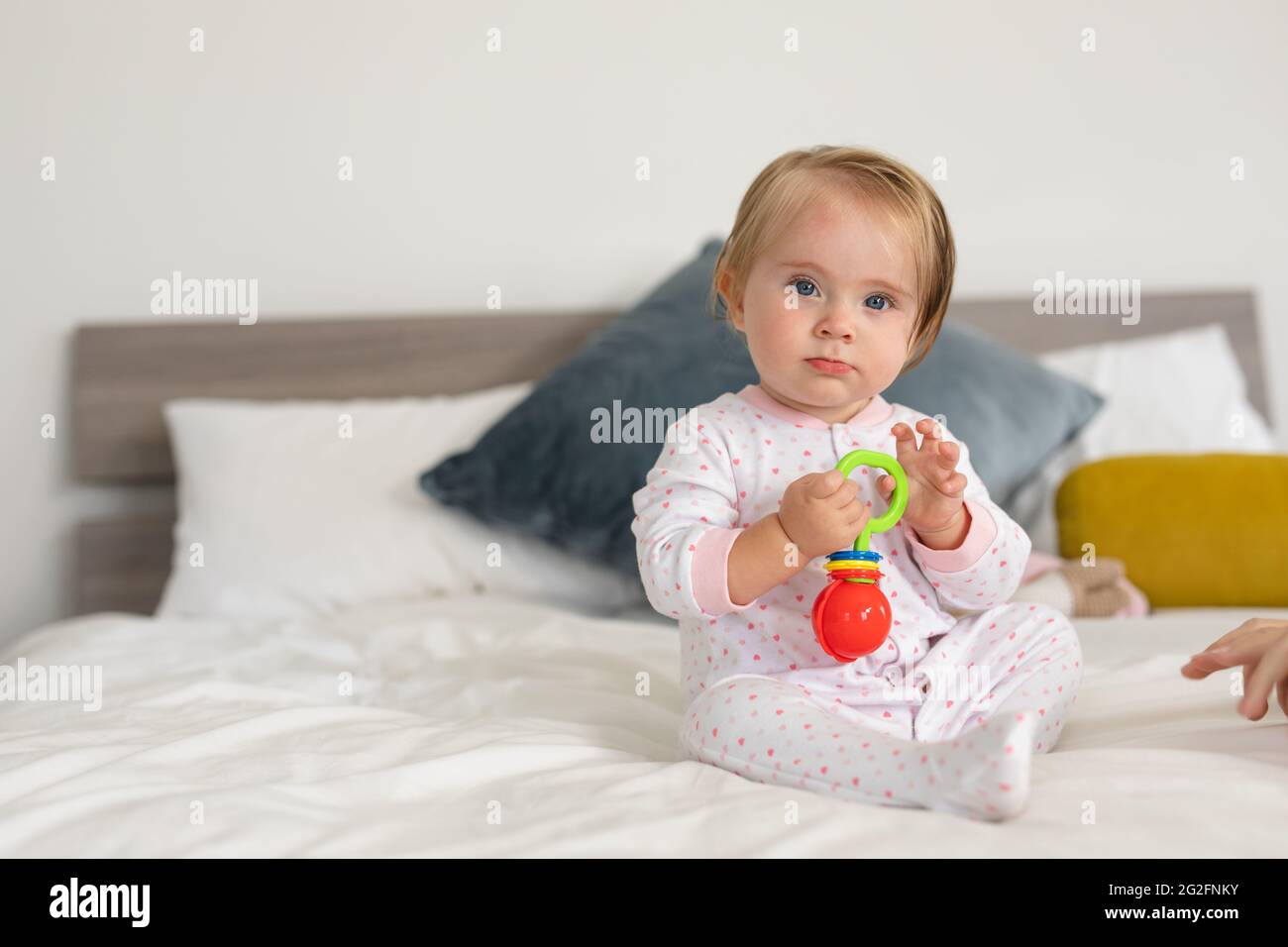 Portrait d'un bébé caucasien jouant avec un jouet tout en étant assis sur le lit à la maison Banque D'Images