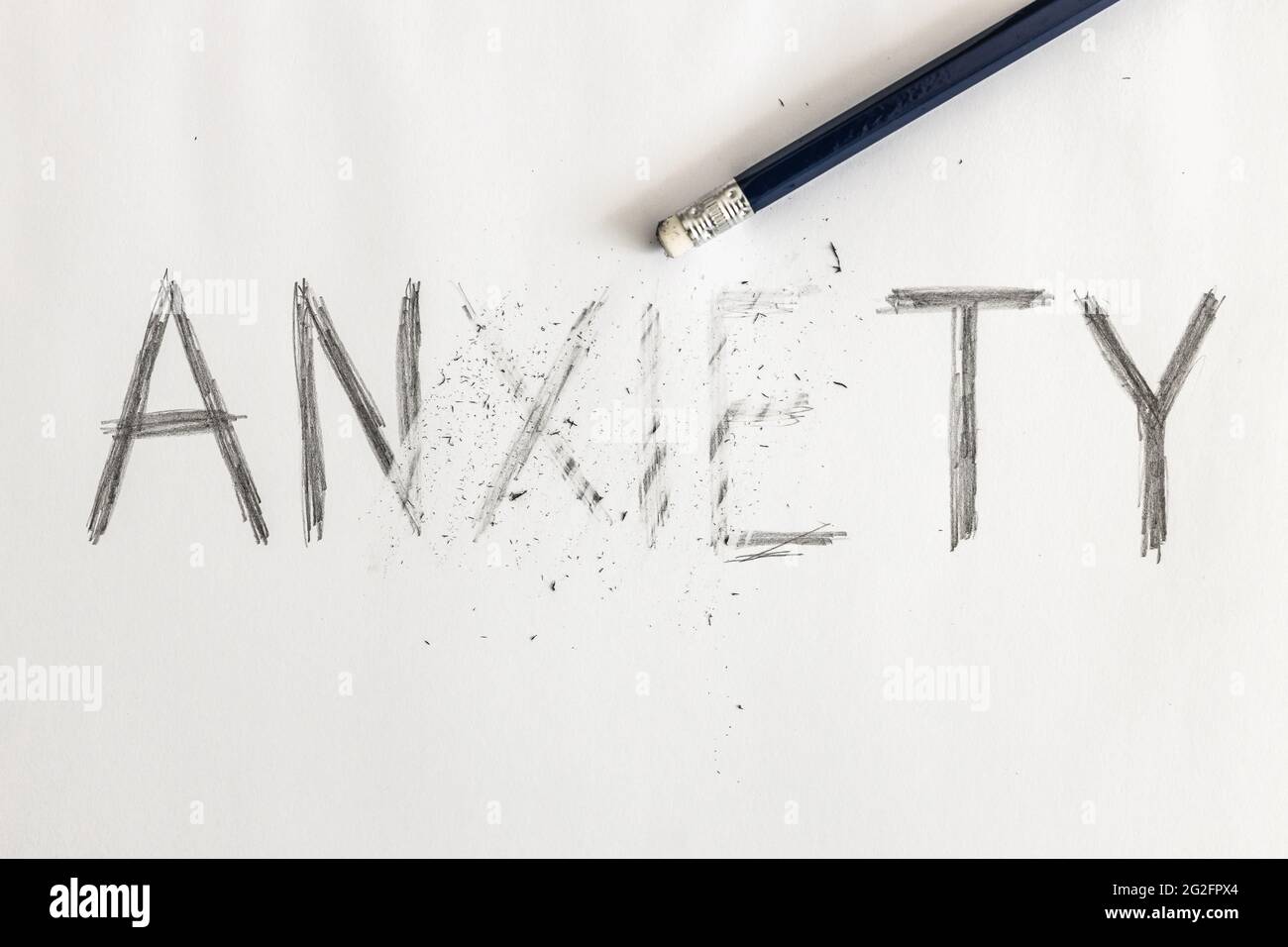 Effacer l'anxiété. Anxiété écrite sur papier blanc avec un crayon, partiellement effacée avec une gomme. Symbolique pour surmonter l'anxiété ou traiter l'anxiété. Banque D'Images