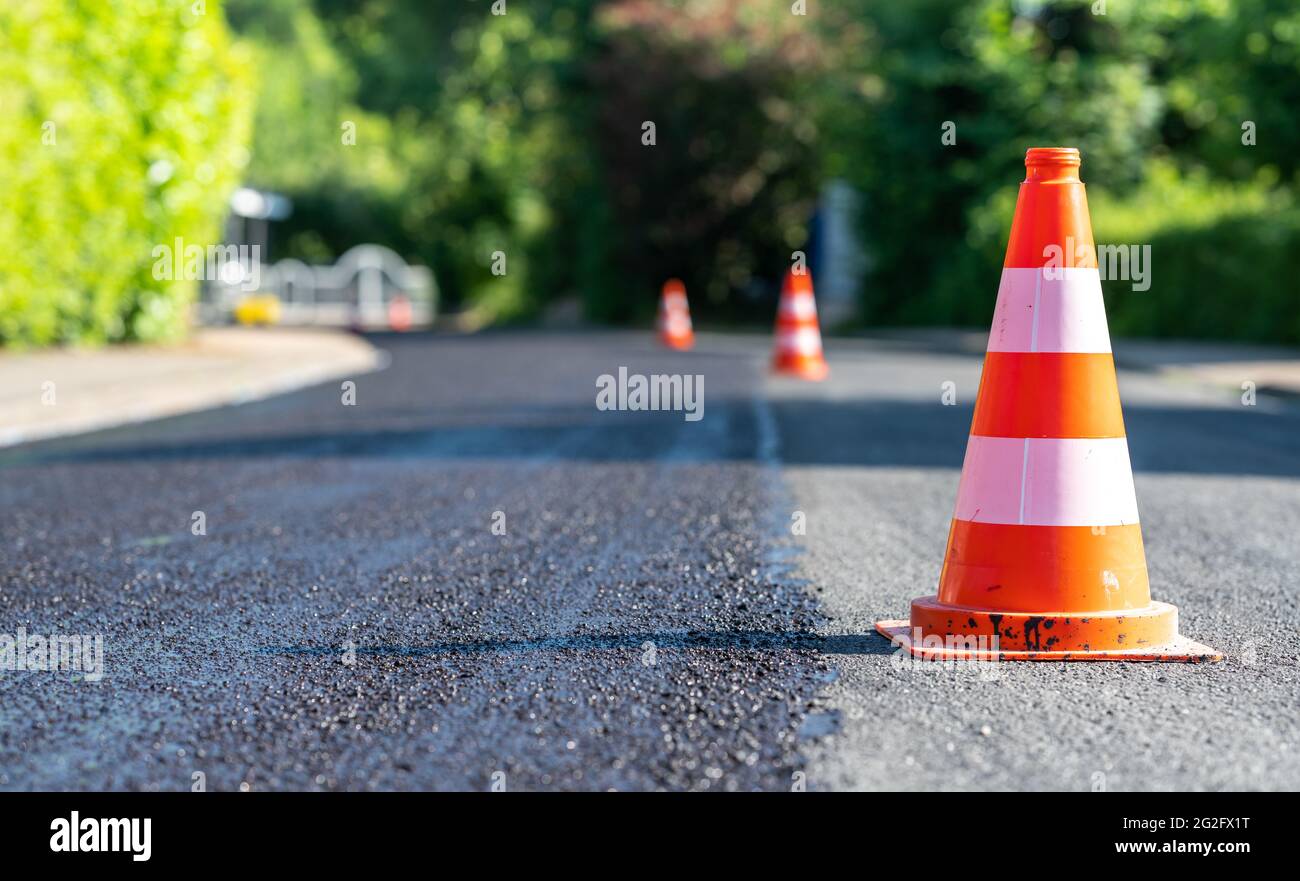 Cônes de construction marquant une partie de la route avec une couche d'asphalte frais. Banque D'Images