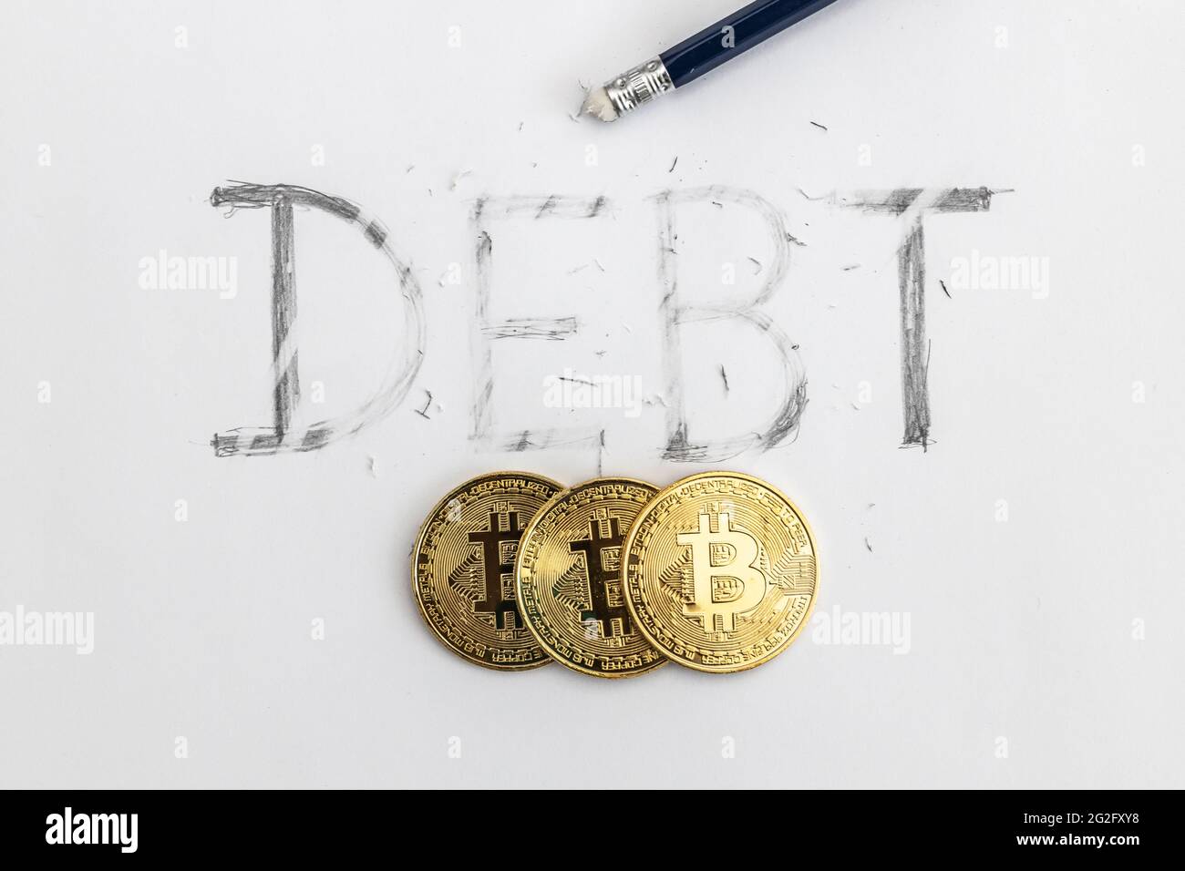 Effacer la dette avec bitcoin. Dette écrite sur papier blanc avec un crayon, partiellement effacée avec une gomme. Symbolique pour effacer la dette. Banque D'Images