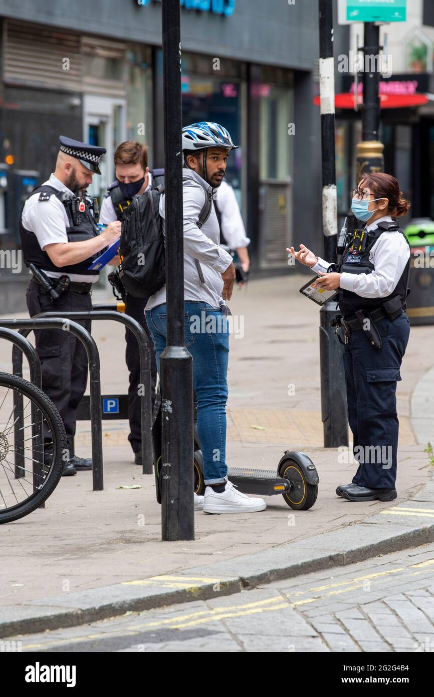 Un pilote E-Scooter arrêté par la police pour le conduire illégalement sur Charing Cross Road à Londres.des scooters électriques sont maintenant disponibles à la location dans un certain nombre de quartiers de Londres. C'est la seule façon de conduire légalement un e-scooter sur la voie publique ou dans d'autres lieux publics de Londres. Banque D'Images