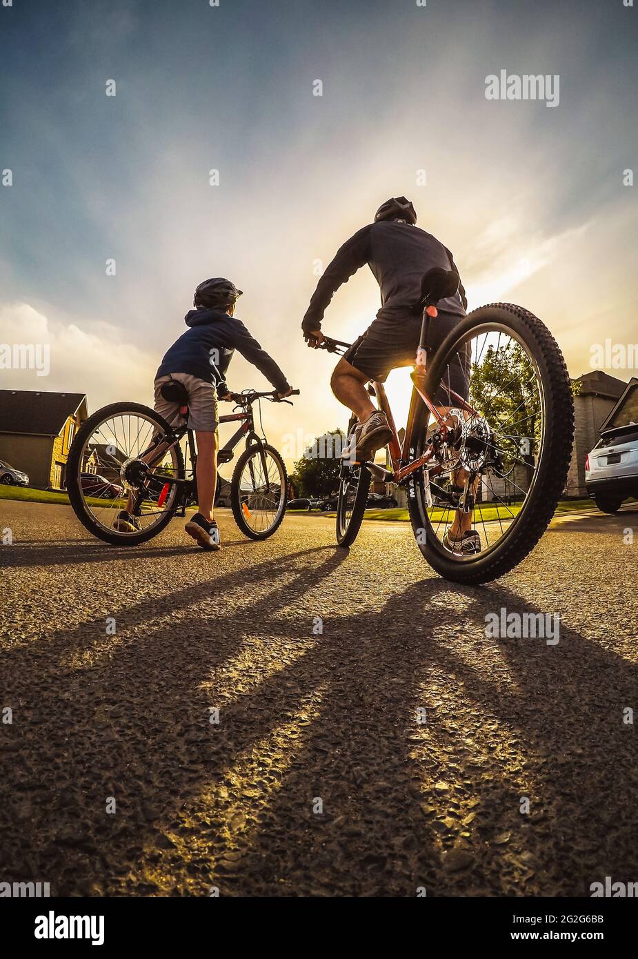 Prise de vue grand angle d'un père et d'un enfant en vélo en soirée. Banque D'Images