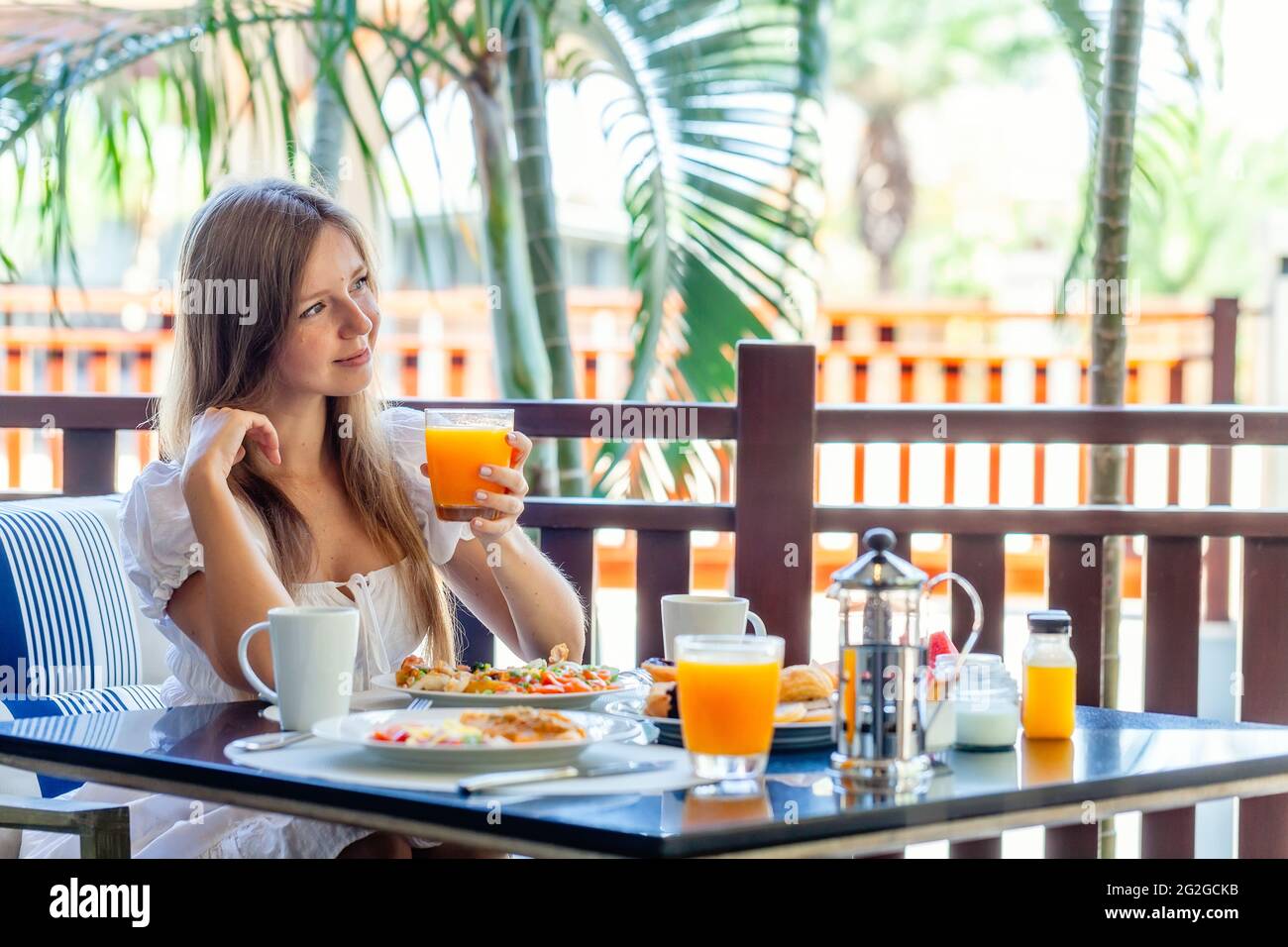 Jeune femme souriante assise sur le petit déjeuner avec des assiettes pleines de Nourriture Banque D'Images