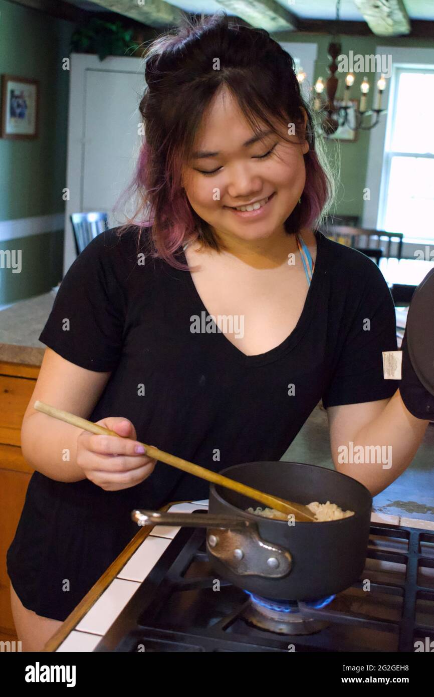 CLASSE DE travail AMÉRICAINE femme cuisant de la nourriture dans la cuisine Banque D'Images