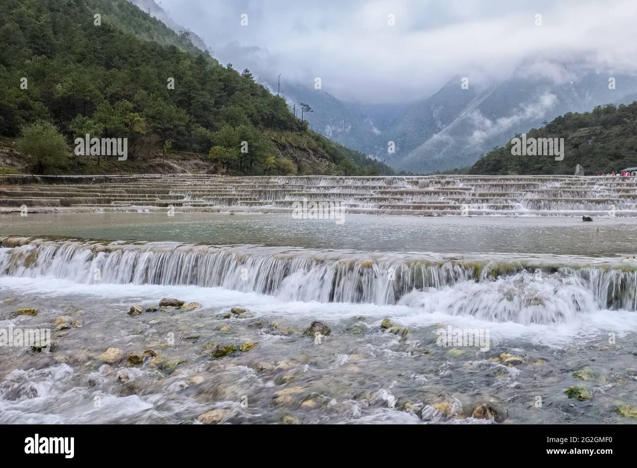 Cascades en cascade de la rivière Baishui entourée par les pics couverts de brouillard de la montagne enneigée du Dragon de Jade dans la vallée de la Lune Bleue, Yunnan, Chine Banque D'Images