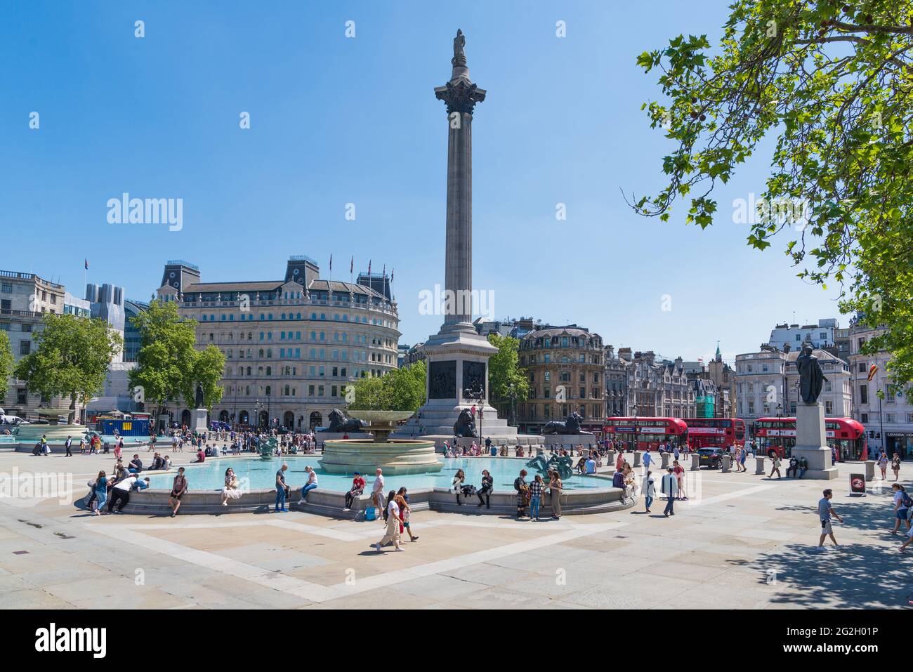 Les gens se détendent et profitent d'une journée chaude et ensoleillée à Trafalgar Square, Londres, Angleterre, Royaume-Uni Banque D'Images