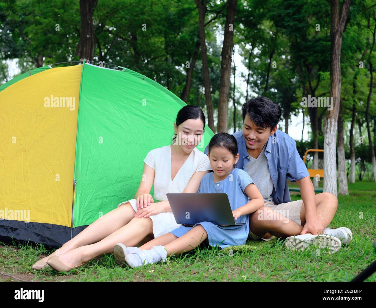 Une famille heureuse de trois personnes utilise un ordinateur pour surfer sur Internet en plein air de haute qualité photo Banque D'Images