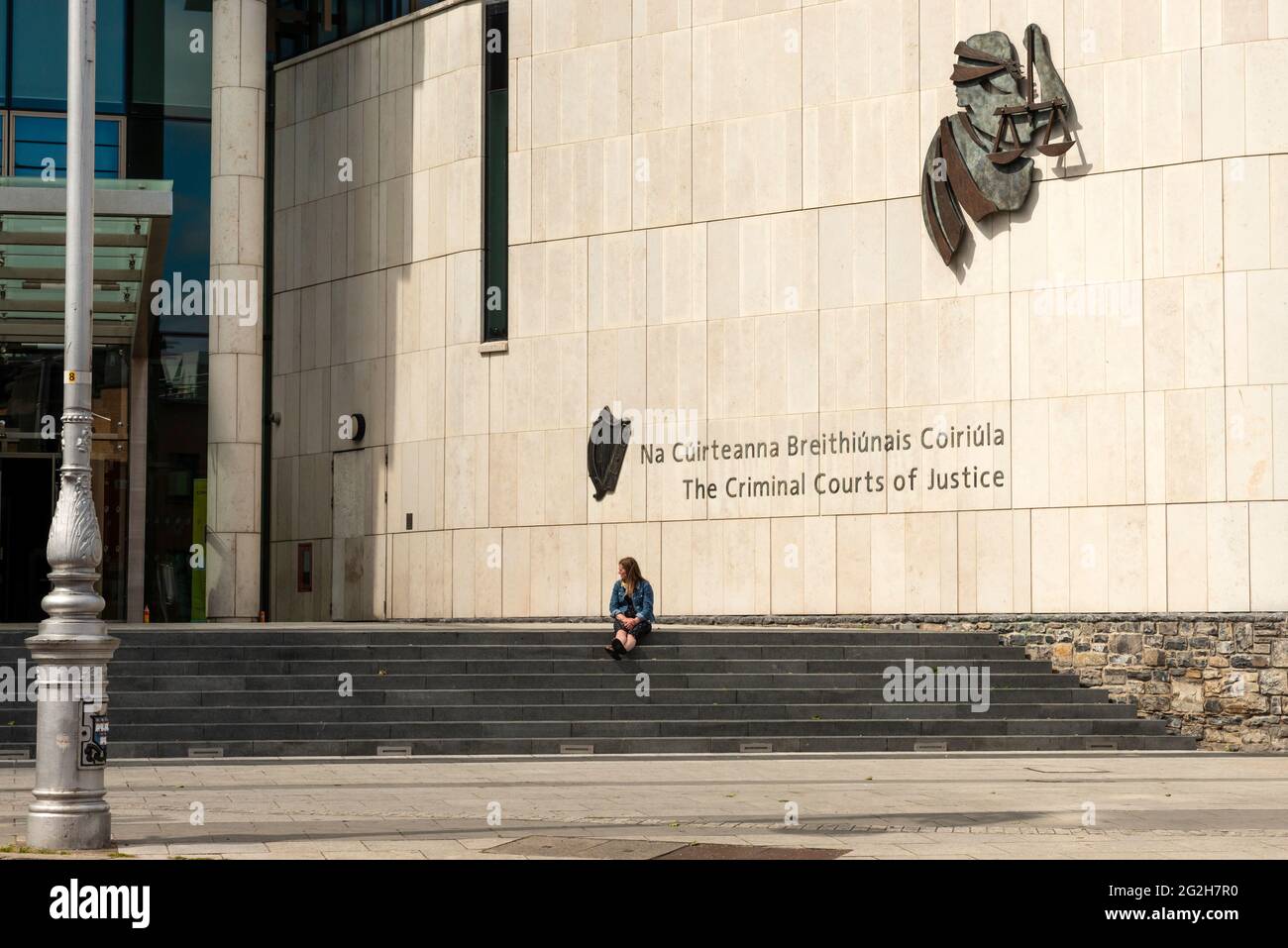 Cour Irlande les cours pénales de justice et une jeune femme seule assise sur les escaliers de la Cour pénale de Dublin, Irlande à partir de juin 2021 Banque D'Images