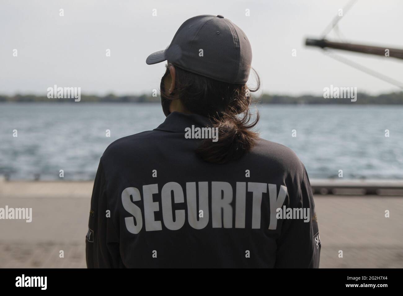 Gros plan d'une garde de sécurité féminine en uniforme et masque observant la région du port Banque D'Images Gros plan d'une garde de sécurité féminine en uniforme et masque observant la région du port Banque D'Images
